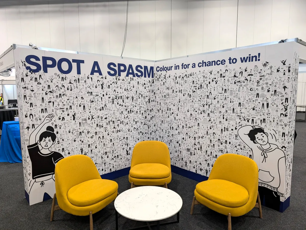 Exhibition stand with illustrated colouring-in wall and yellow lounge seating